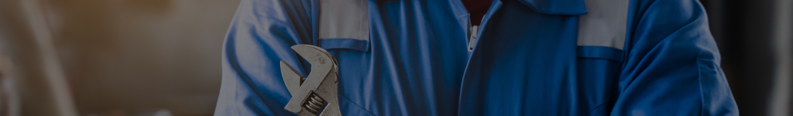 工具（レンチ）を持ち、作業服を着た修理スタッフ